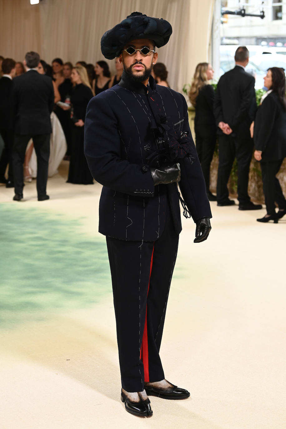 Bad Bunny, anfitrión de esta edición, eligió un traje sastre de Maison Margiela. Es un diseño en azul marino con los hilvanes blancos a la vista. El pantalón incluía, además, un detalle rojo. Lo combinó con guantes de cuero y una boina XXL. 