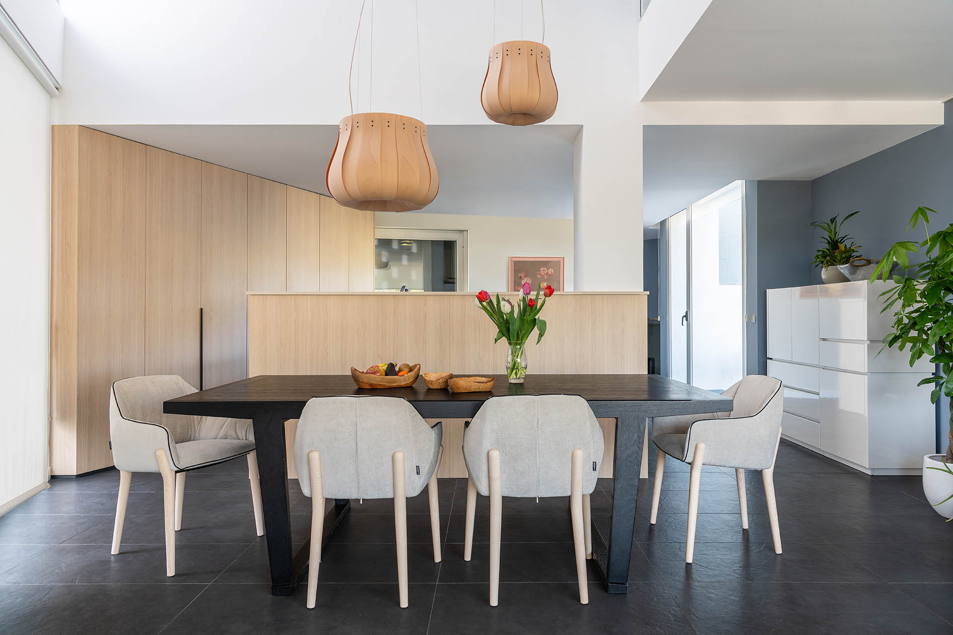 La cocina presenta gabinetes de madera que ocultan los electrodomésticos, un espacio que se comunica con una zona de comedor con una mesa con capacidad para seis comensales