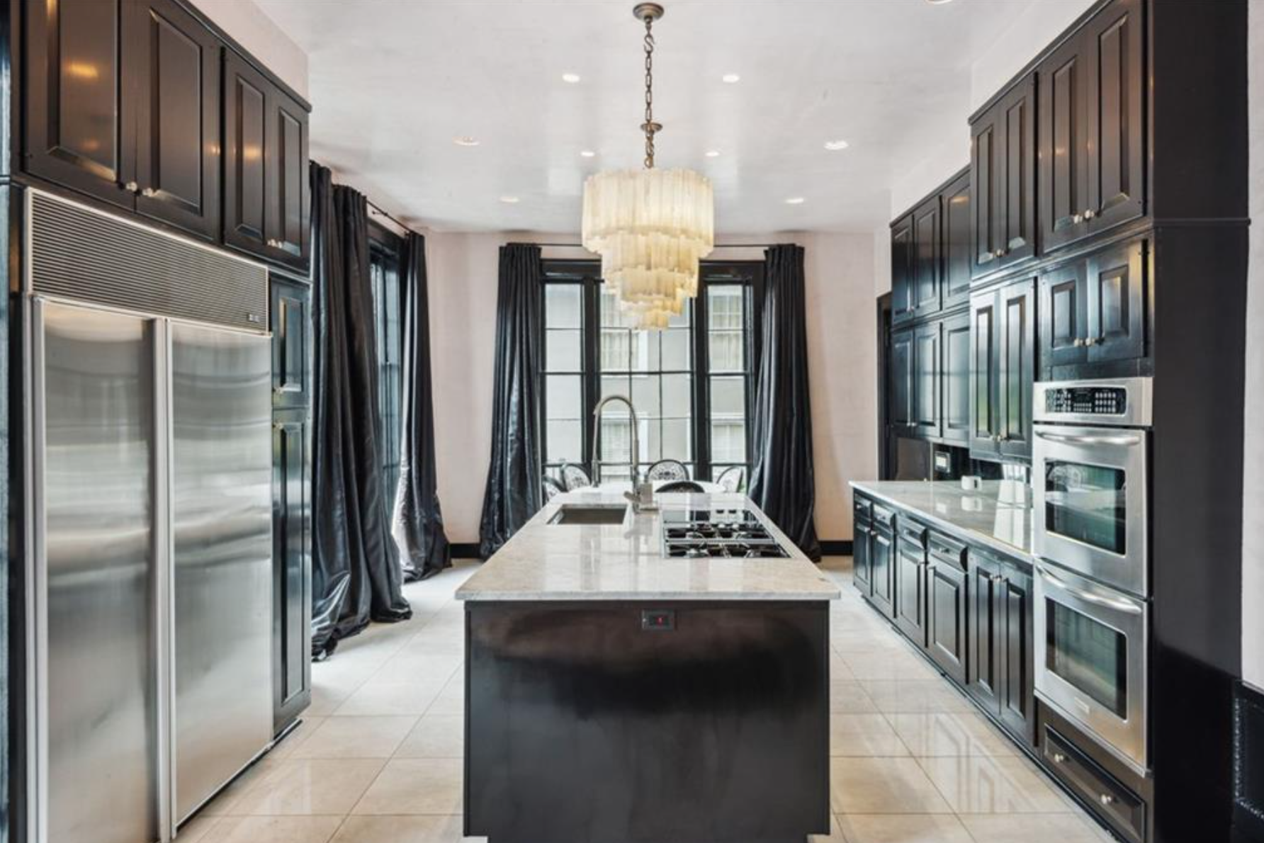 La cocina cuenta con gabinetes de color negro, electrodomésticos de alta gama de acero inoxidable y una isla central 