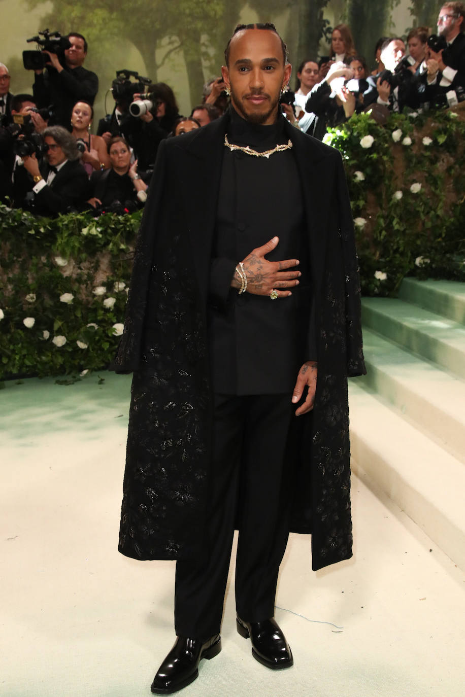 El piloto Lewis Hamilton adora la moda y luce un estilo muy personal. En la Gala Met eligió un total look ennegro con una original capa. 