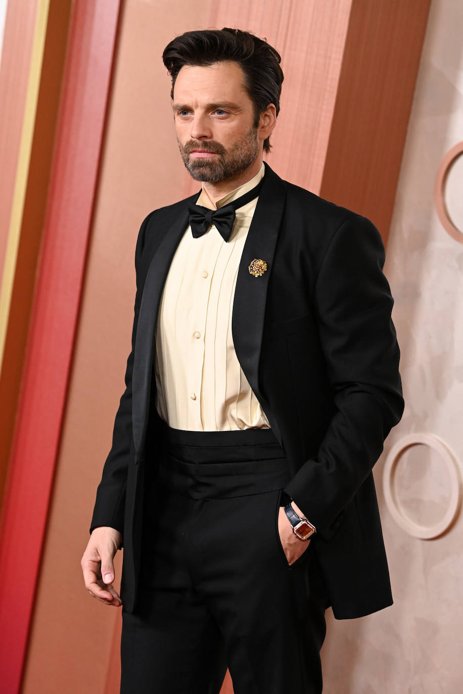 Sebastian Stan también optó por un esmoquin de Prada, que combinó con camisa beige. Completó su look con el Cartier Santos en su muñeca y un broche joya en la solapa. 