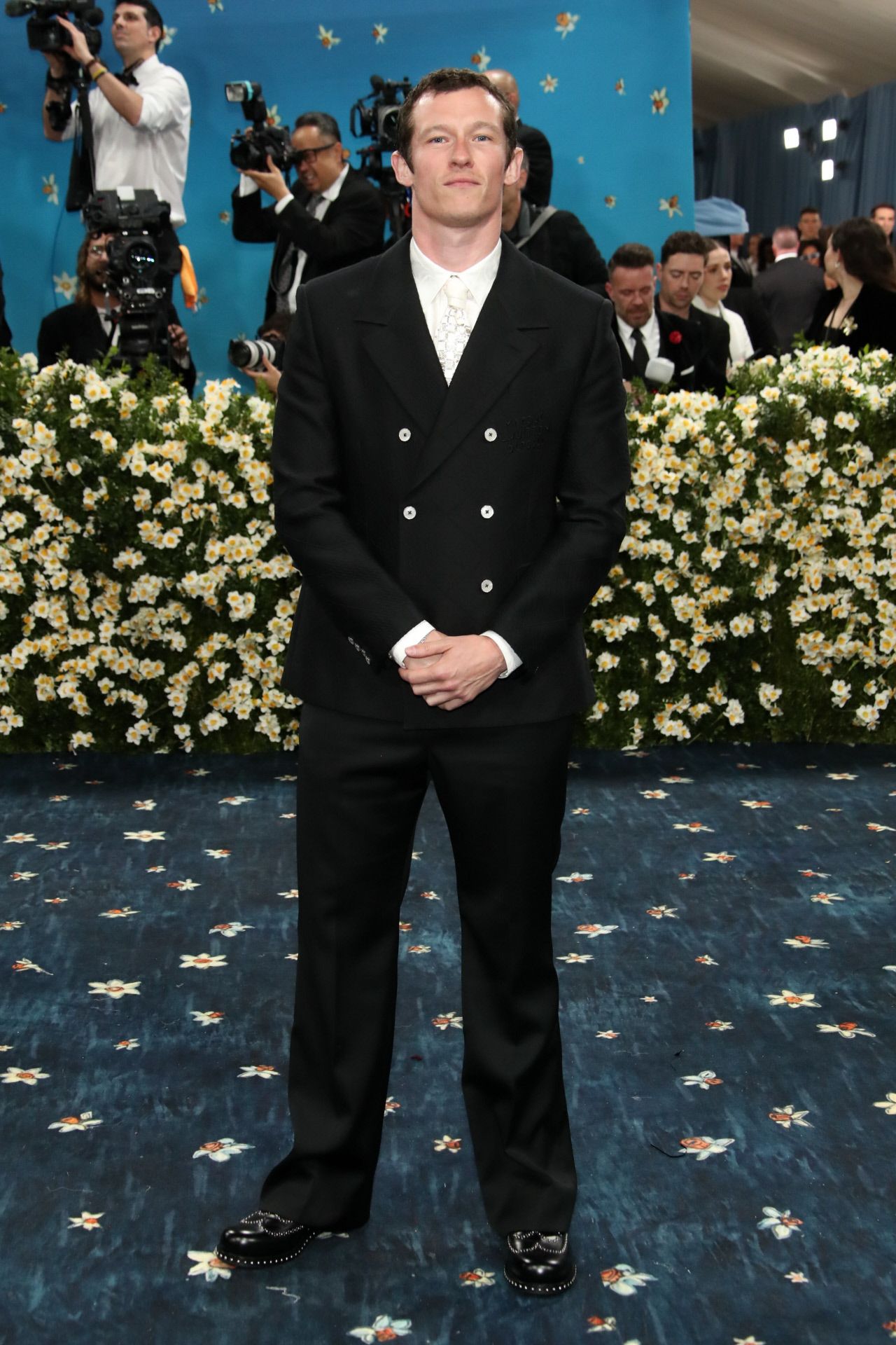 Callum Turner eligió un traje con chaqueta cruzada en color negro, que combinó con camisa y corbata en blanco. 
