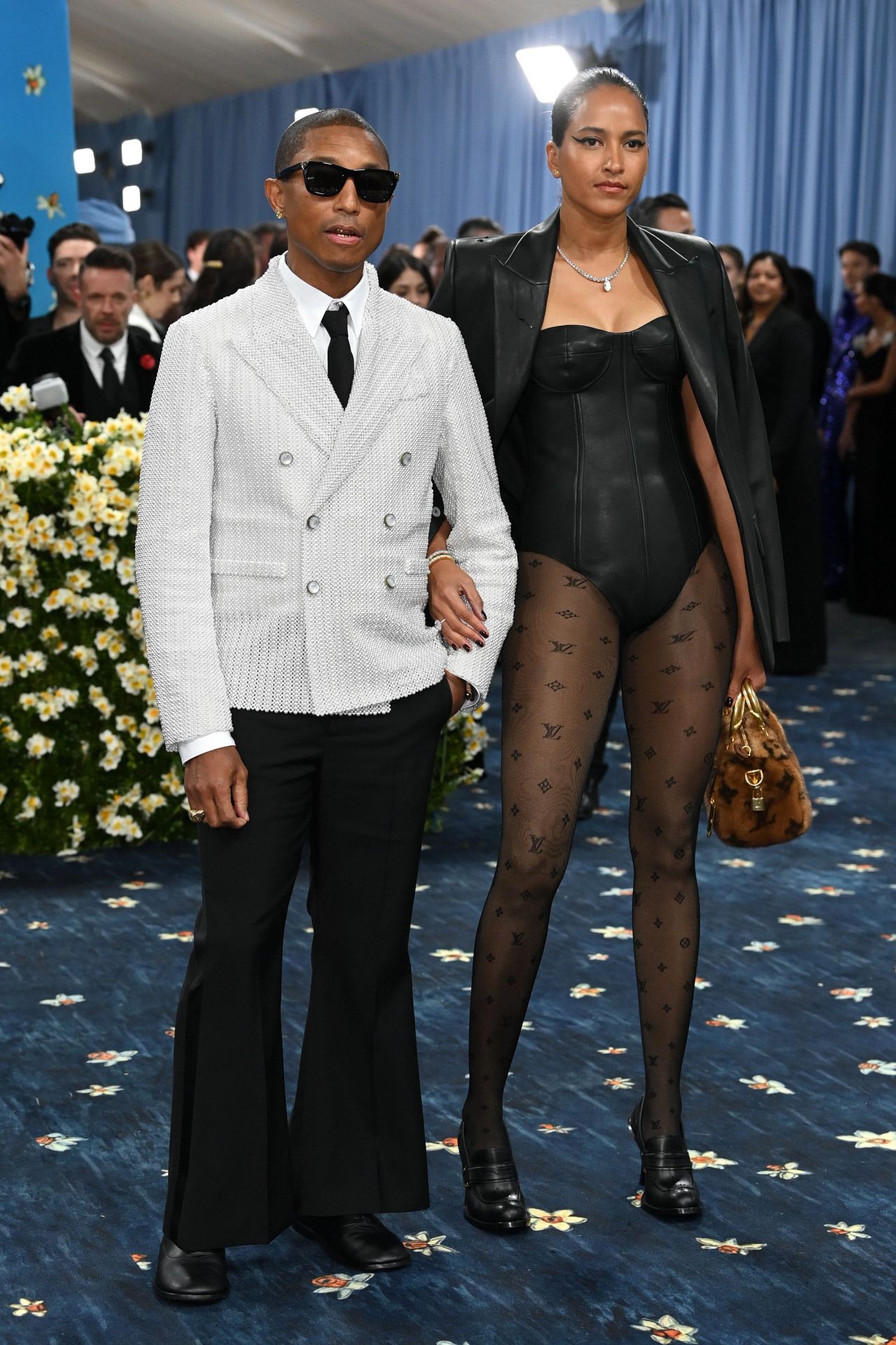 El diseñador Pharrel Williams eligió un traje de Louis Vuitton, compuesto por una chaqueta corta cruzada, confeccionada a mano con perlas blancas, pantalón ancho, camisa blanca de algodón y corbata de seda negra. 