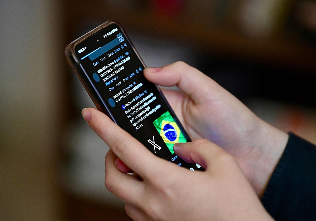 Una usuaria brasileña de la red social X, consulta publicaciones en un teléfono móvil