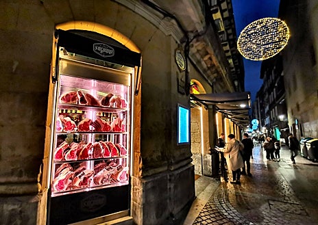 Imagen secundaria 1 - En la foto superior, El Arratiano, una tienda de alimentación y pastelería. Sobre estas líneas, el Asador Sugarra, en la esquina de Calle Santa María, 13 y Calle del Perro. A la derecha. Sombreros Gorostiaga, donde se venden gorras desde 1857.