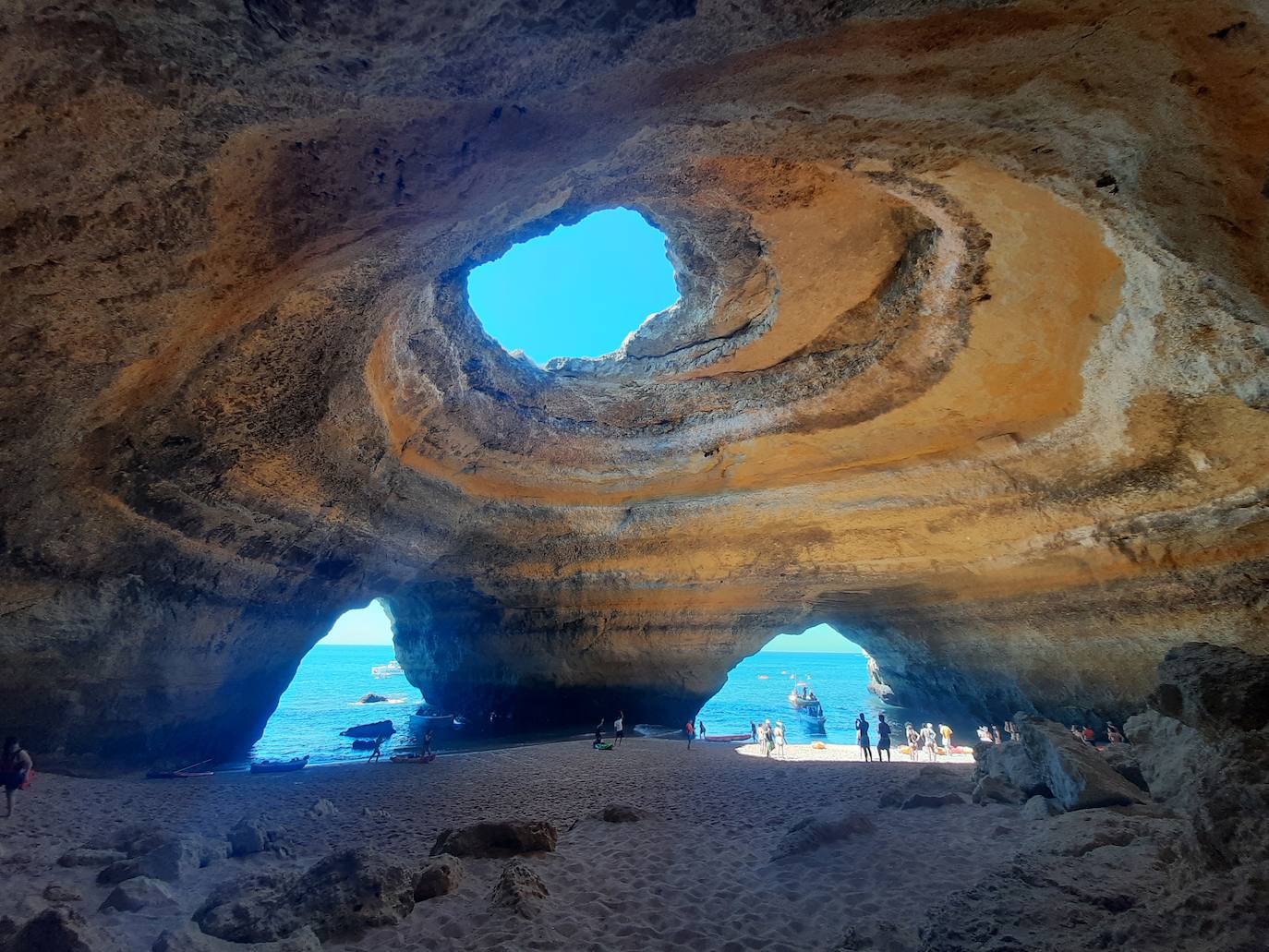 Cueva de Benagil, Algarve (Portugal), 16 078 reseñas. A lo largo de la costa hay numerosas grutas moldeadas por la acción del mar y del viento, y una de las más impresionantes es, sin duda alguna, la cueva de Benagil. Uno de los aspectos que la hace tan llamativa es el enorme agujero en la parte superior, por el que se cuelan los rayos de sol. Esta cueva no es accesible por vía terrestre, por lo que las excursiones en barco son una opción estupenda para explorar la zona y descubrir todo su encanto.