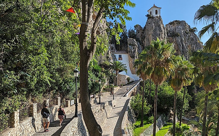 Imagen principal - En frente del castillo de San José están los restos del Castillo de la Alcozaiba, también del siglo XI, con un complicado acceso (no se puede visitar) del que sólo queda una torre en ruinas. Sobre estas líneas, el túnel que da acceso a la zona con más historia de Guadalest, y la plaza en agosto, en días de fiesta