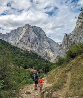 Imagen secundaria 2 - La cumbre del Naranjo de Bulnes está a 2.519 metros sobre el nivel del mar. A diez minutos a pie desde Bulnes está el mirador que podemos ver en la foto superior, en el que que se aprecia la reconocible silueta de esta montaña. En el pueblo comienzan infinidad de rutas por estas montañas. A la izquierda, el cementerio, en los Picos de Europa.