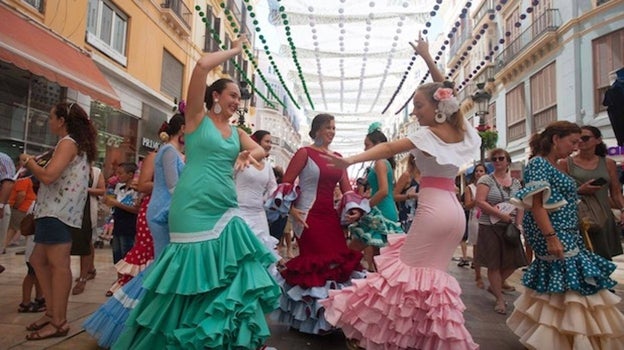 Mujeres vestidas de flamenca bailando sevillanas durante la Feria de Málaga