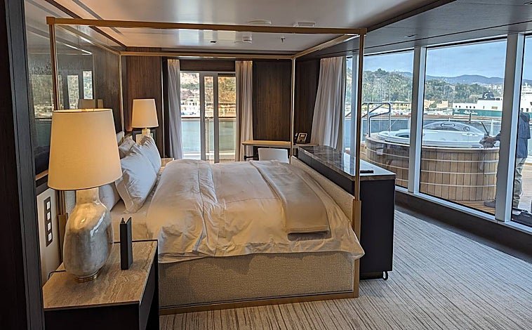 Imagen principal - El Regent Seven Seas Cruises puede acoger a 746 pasajeros -en 375 suites- y 548 tripulantes, una proporción que acentúa la sensación de lujo que nos rodea. En la foto superior, una de las dos habitaciones de la Regent Suite. Sobre estas líneas, a la izquierda, la biblioteca del barco; a la derecha, la entrada al barco.