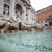 Un trabajador de la empresa de servicios públicos ACEA utiliza una escoba para recoger monedas en la Fontana de Trevi, Roma.  Luego, las monedas se entregan a Cáritas