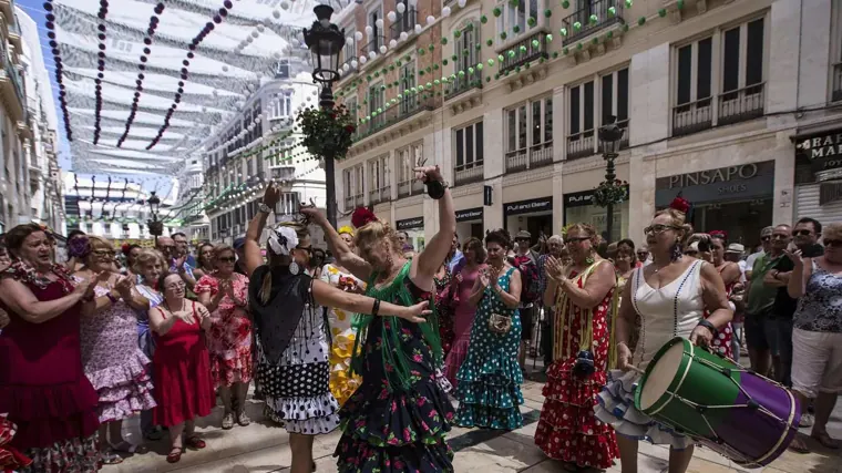 Mujeres bailando sevillanas durante la Feria de Málaga en la calle Larios
