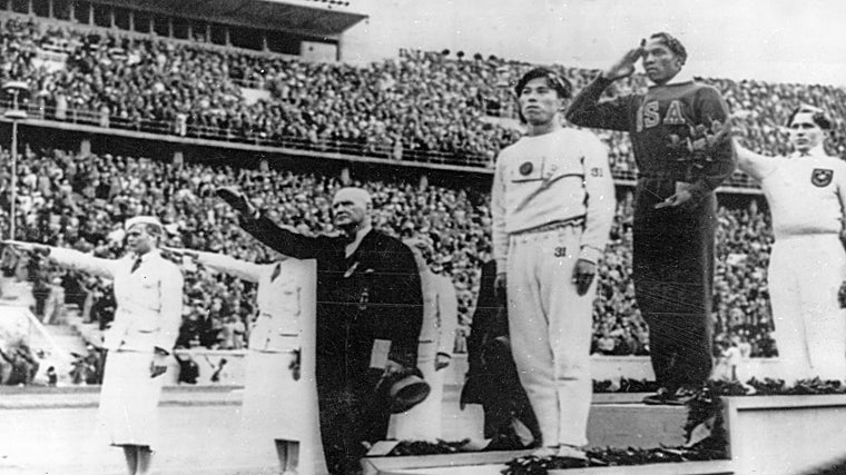 Owens saluda durante la ceremonia de entrega de medallas en la prueba de salto de longitud en el estadio Olímpico de Berlín, mientras otros hacen el saludo nazi. Owen consiguió 4 medallas en los juegos.