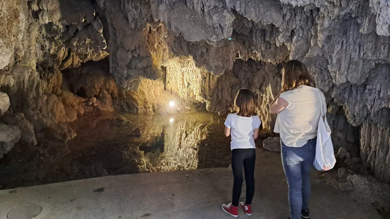 Dos visitantes ante una de las grutas, iluminada