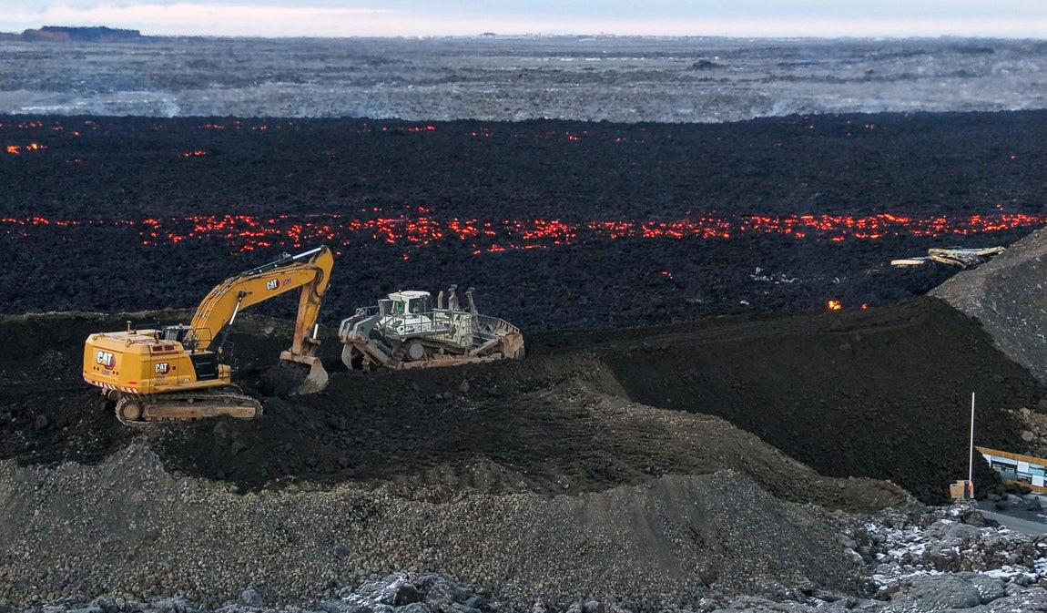 Las excavadoras trabajan para intentar bloquear el flujo de lava que rodea el estacionamiento de Blue Lagoon.