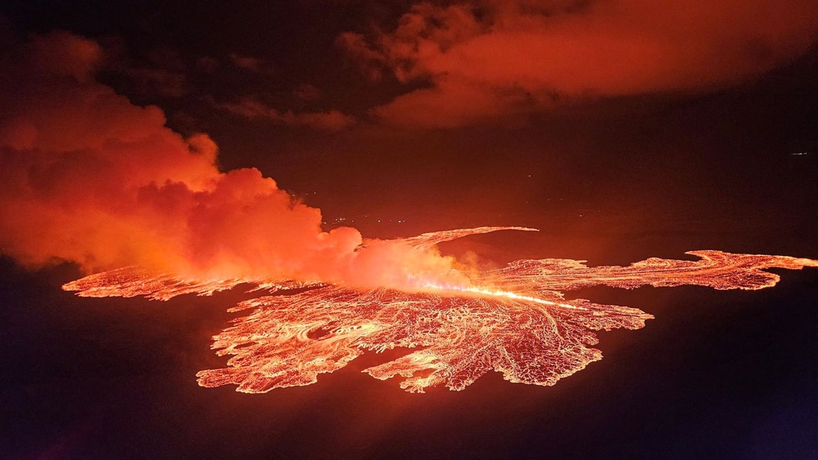 La lava brota y fluye tras la erupción de un volcán en la península de Reykjanes, cerca de Grindavik, Islandia. El volcán en erupción pertenece al tipo de “volcán rojo”, caracterizado por la emisión de lava fluida que fluye tranquilamente a través de fisuras o cráteres, creando ríos de magma. Este comportamiento contrasta con los “volcanes grises”, que suelen tener erupciones explosivas y emiten cenizas, gases y fragmentos de roca debido a la viscosidad del magma y la acumulación de gases a alta presión.