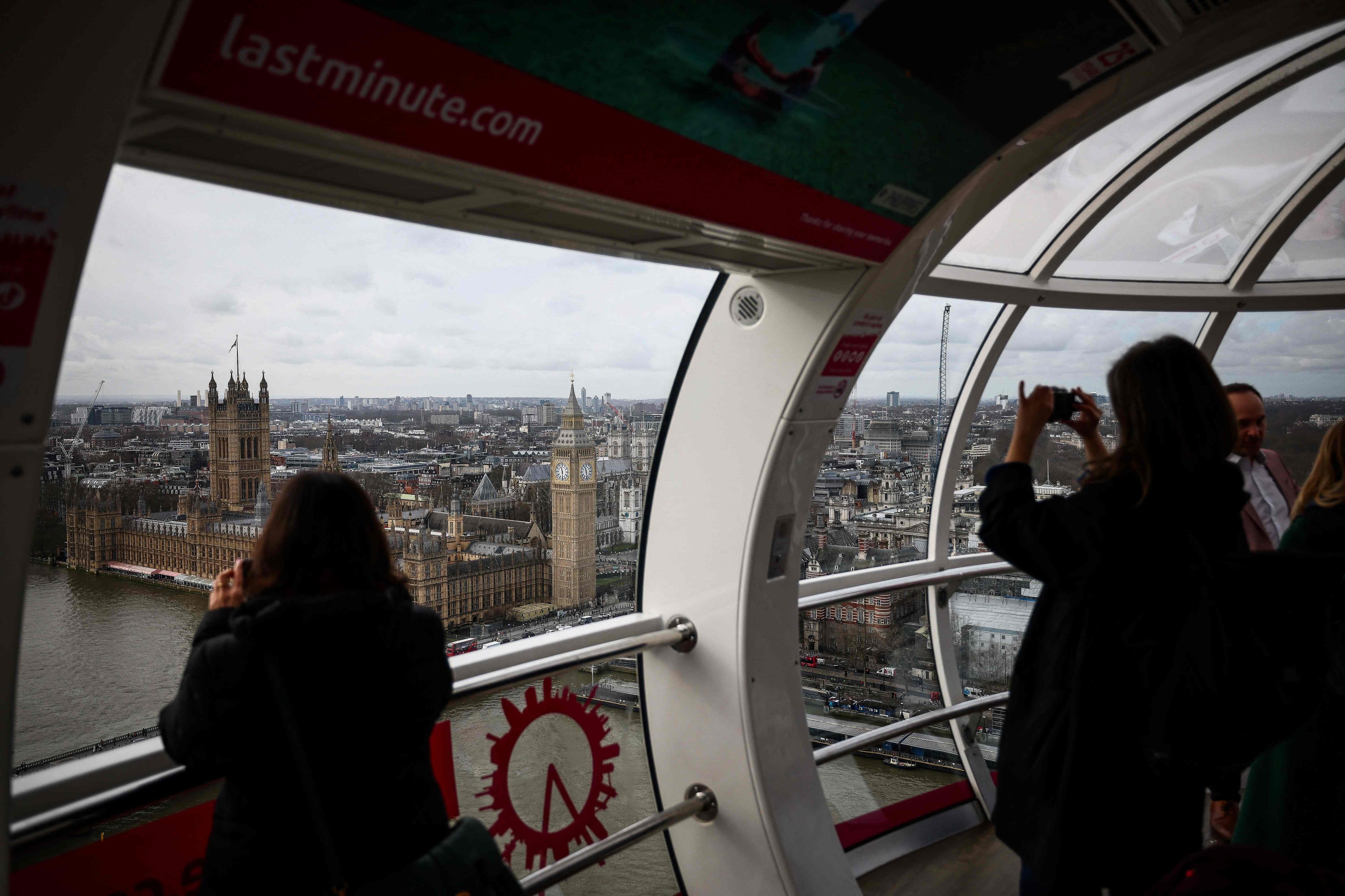 Turistas fotografían el Big Ben y el Palacio de Westminster mientras disfrutan de un recorrido en el London Eye.