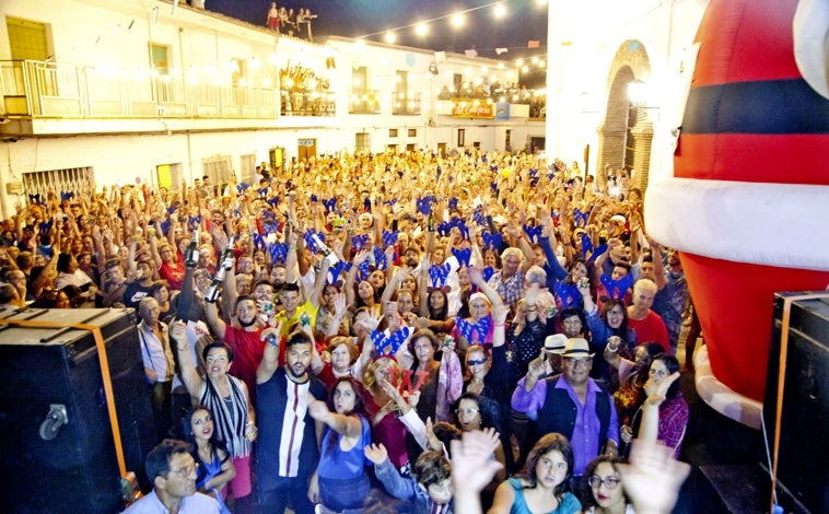 Imagen principal - La gran fiesta de Nochevieja en la plaza de la Iglesia (arriba); Vecinas cantando villancicos (abajo izquierda) y uno d elos árboles de Navidad que decoran el municipio (abajo izquierda)