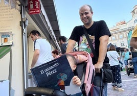 Una niña ojea El Ratoncito Pérez, mientras es llevada en carrito por su padre
