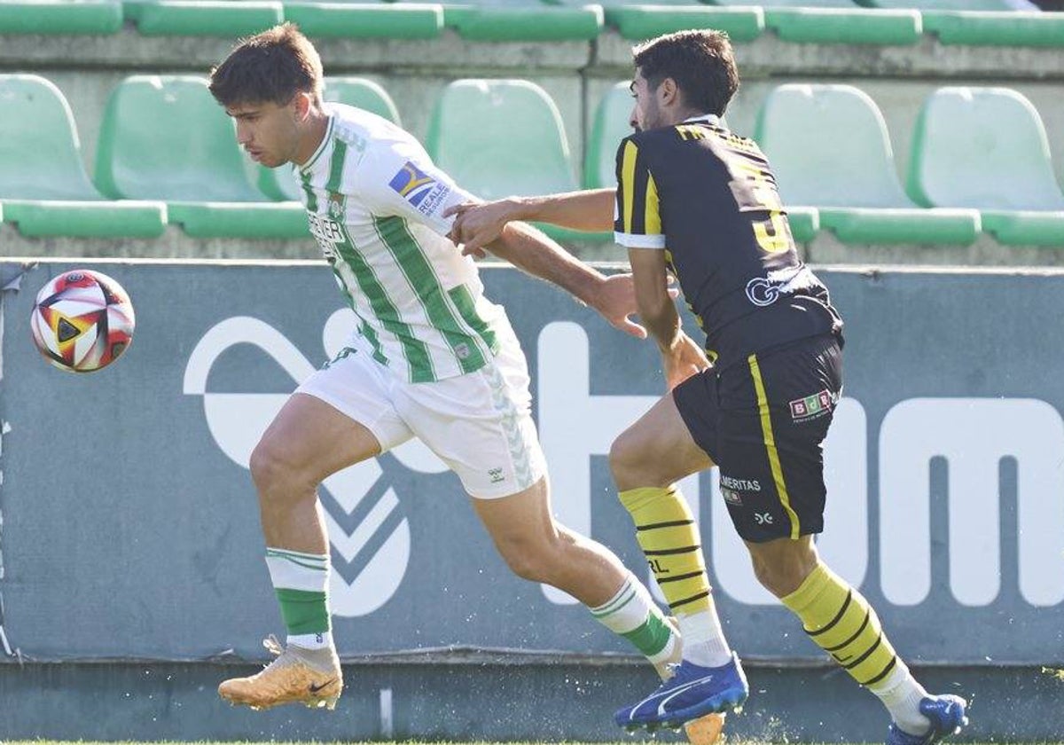 Fran Ávila tratando de sujetar a un futbolista del Betis Deportivo