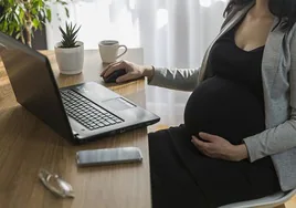 Imagen de archivo de una mujer embarazada sentada delante de un ordenador