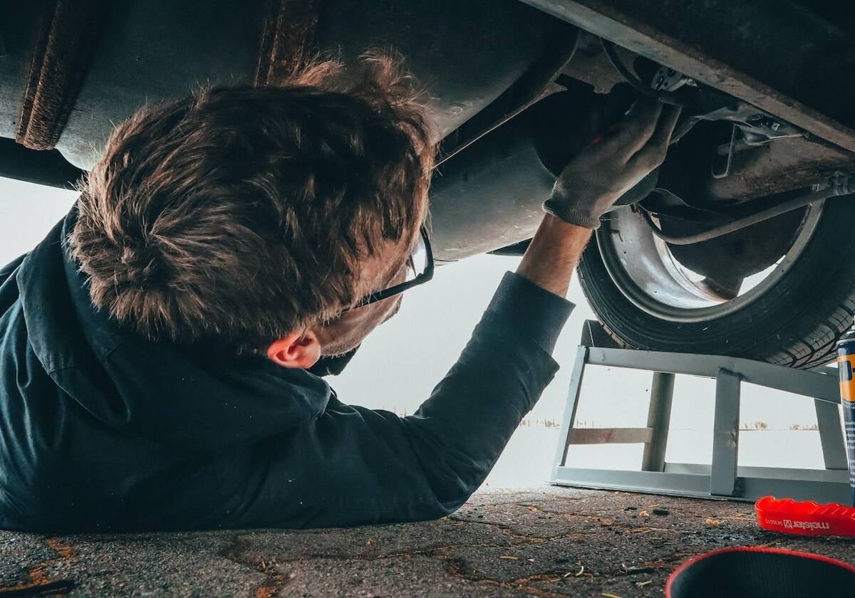 Un mecánico arreglando un desperfecto en un automóvil en su taller