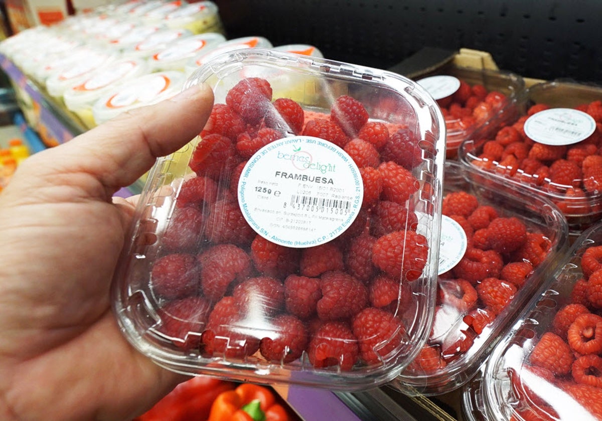 Una persona sujeta un envase de frambuesas en un supermercado Mercadona