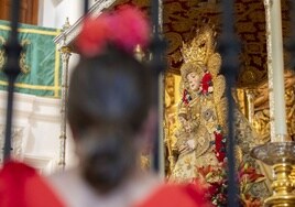 Una devota rociera reza entre las rejas ante la Virgen del Rocío
