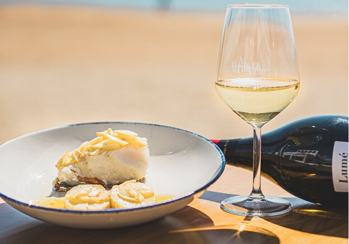 Plato y vino servido en Mar de Kñas, uno de los bares donde comer bien y barato en las playas de Huelva