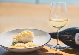 Plato y vino servido en Mar de Kñas, uno de los bares donde comer bien y barato en las playas de Huelva