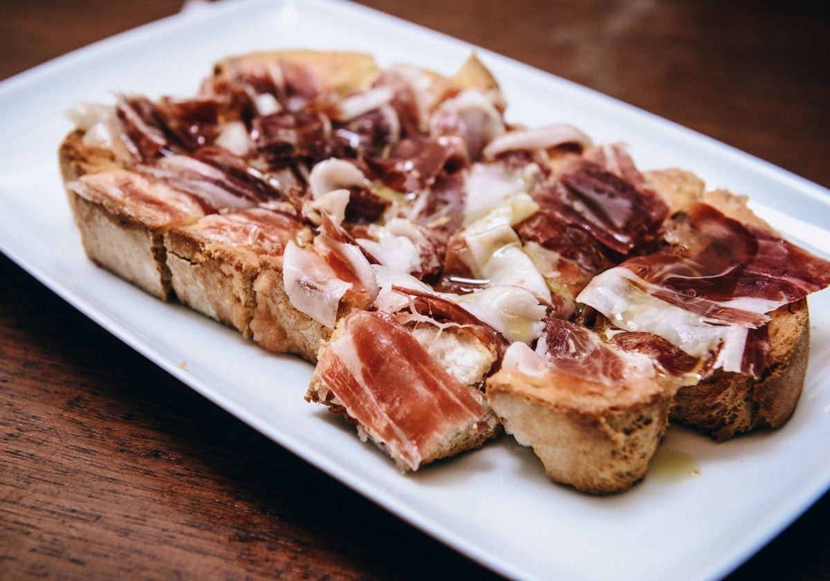 Tosta de pan con jamón servida en la taberna de Huelva que es un templo de la chacina ibérica y las carnes