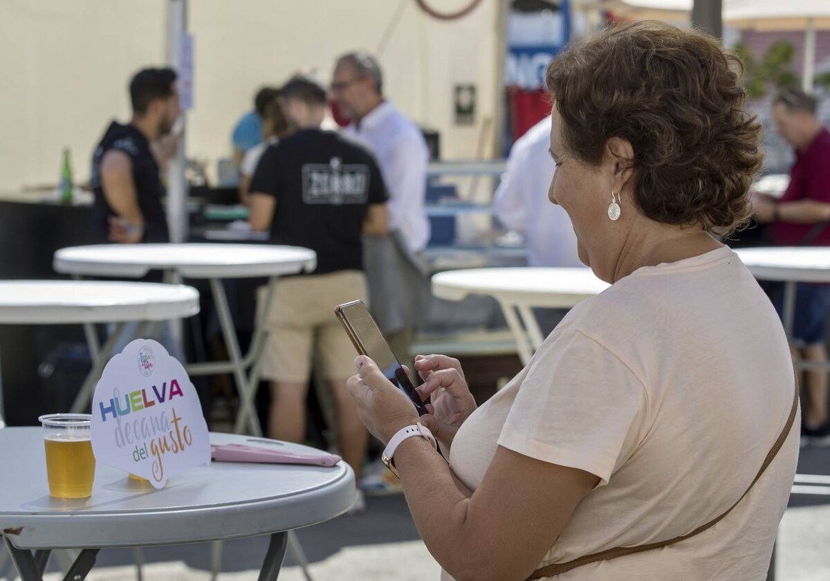 Una señora fotografía el lema de la Feria de la Tapa de Huelva