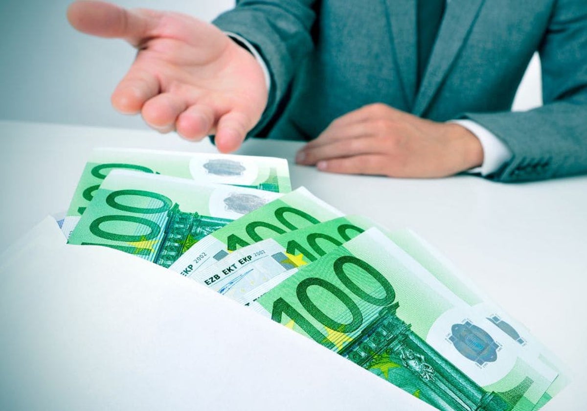 Imagen de archivo de una persona recibiendo un sobre con billetes de cien euros
