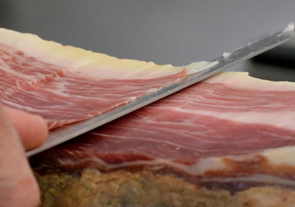 Foto de archivo de una persona cortando jamón