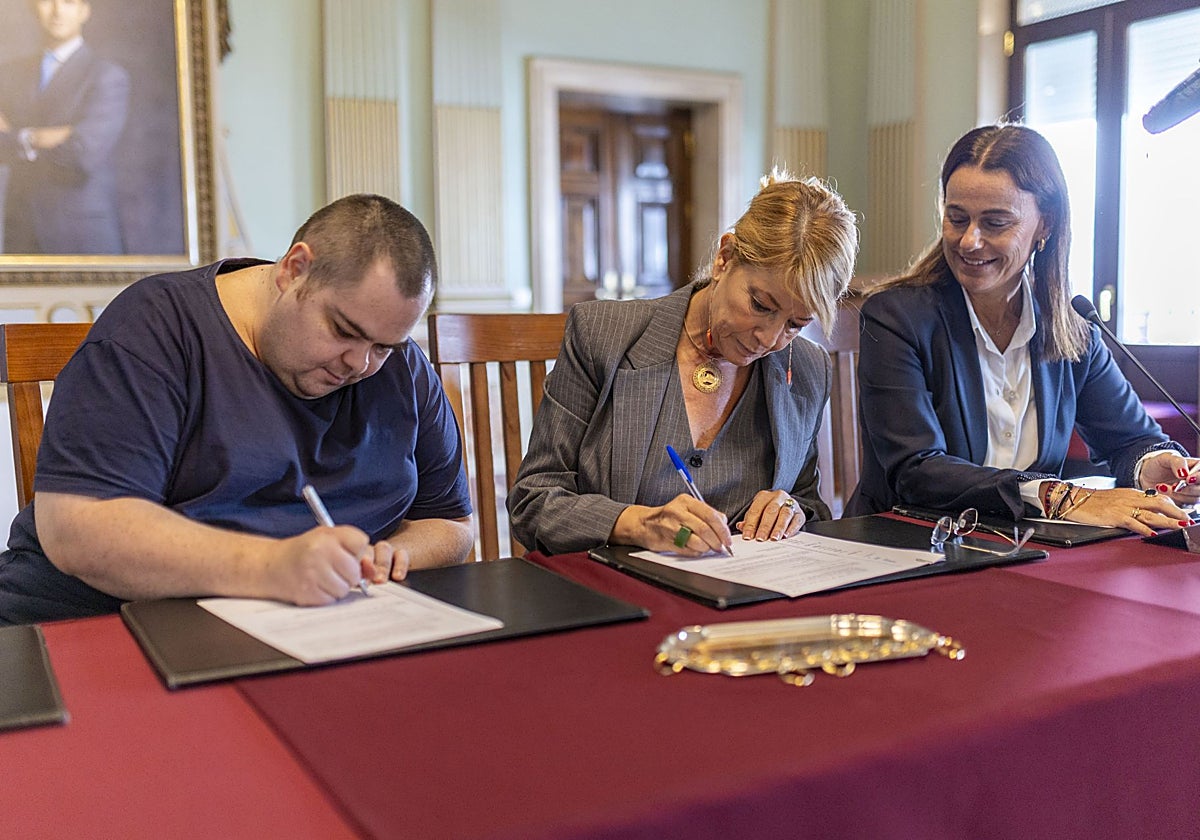 Uno de los beneficiarios de las 14 viviendas sociales firmando el contrato junto a la alcaldesa de Huelva