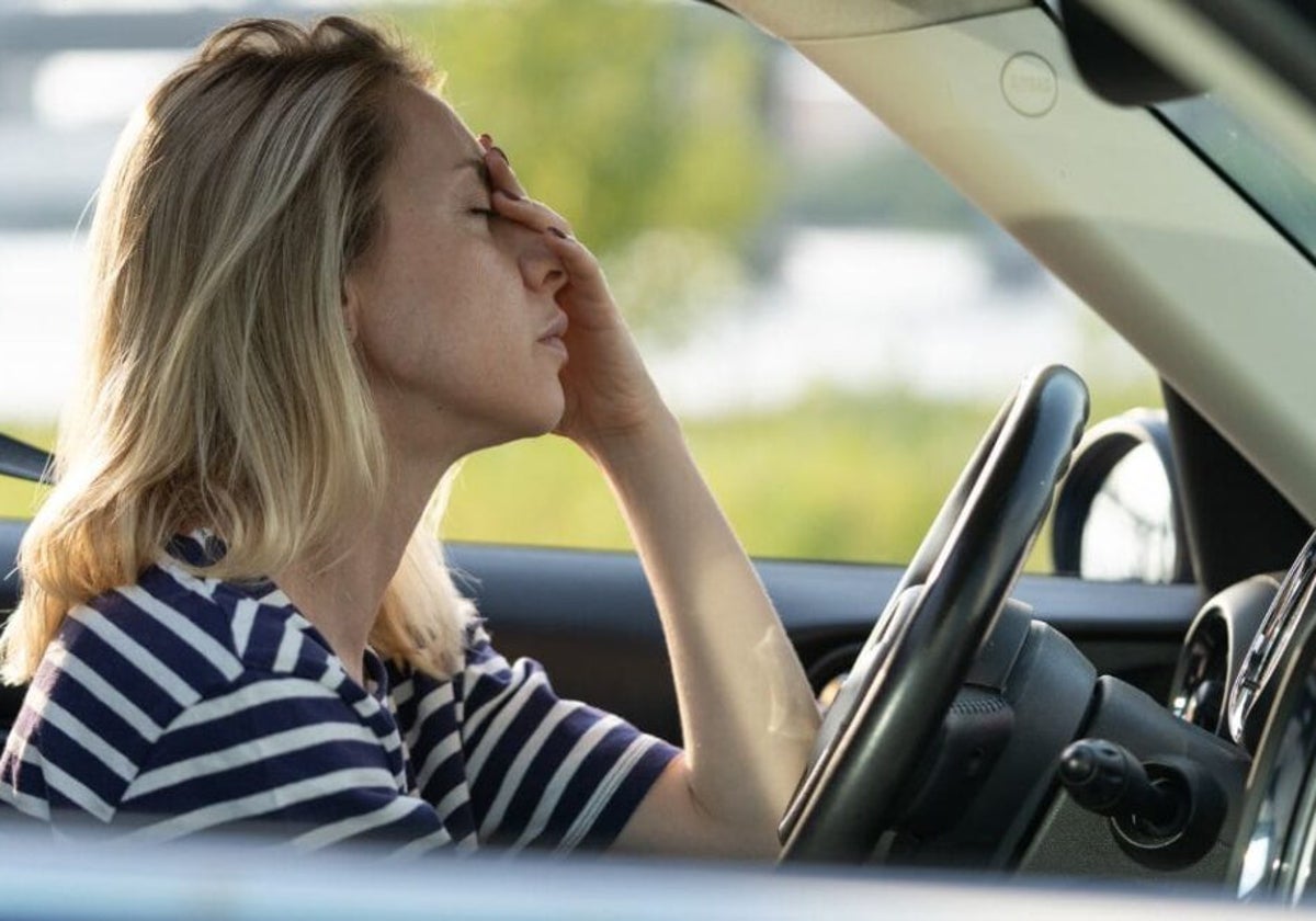 Imagen de archivo de una mujer con dolor de cabeza al volante