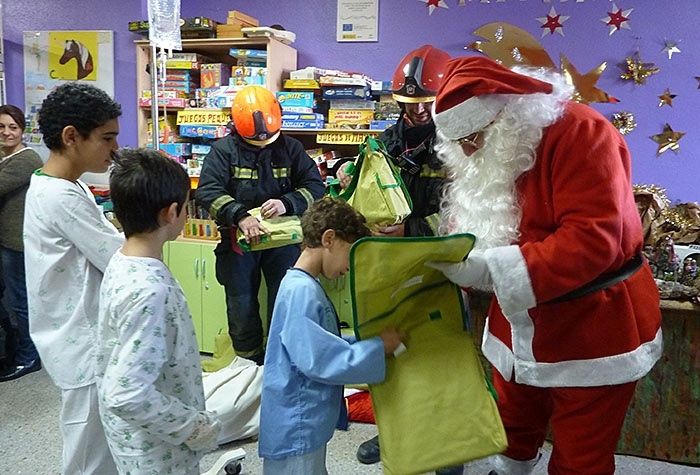 Los bomberos ayudan a Papá Noel en su visita a la Unidad de Pediatría del Hospital Juan Ramón Jiménez