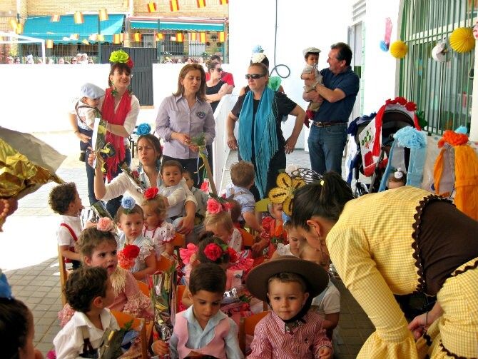Los niños de la guardería Caracola de Punta Umbría hacen una ofrenda floral a la Santa Cruz