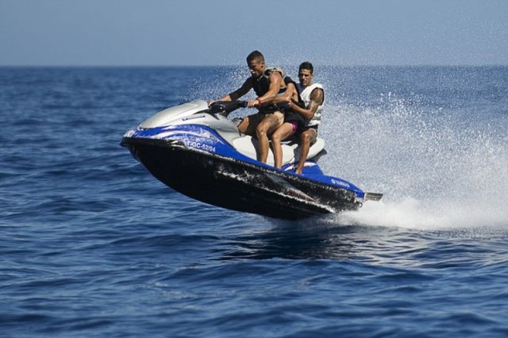 Dos personas recorren las aguas de la Playa de Islantilla en moto de agua