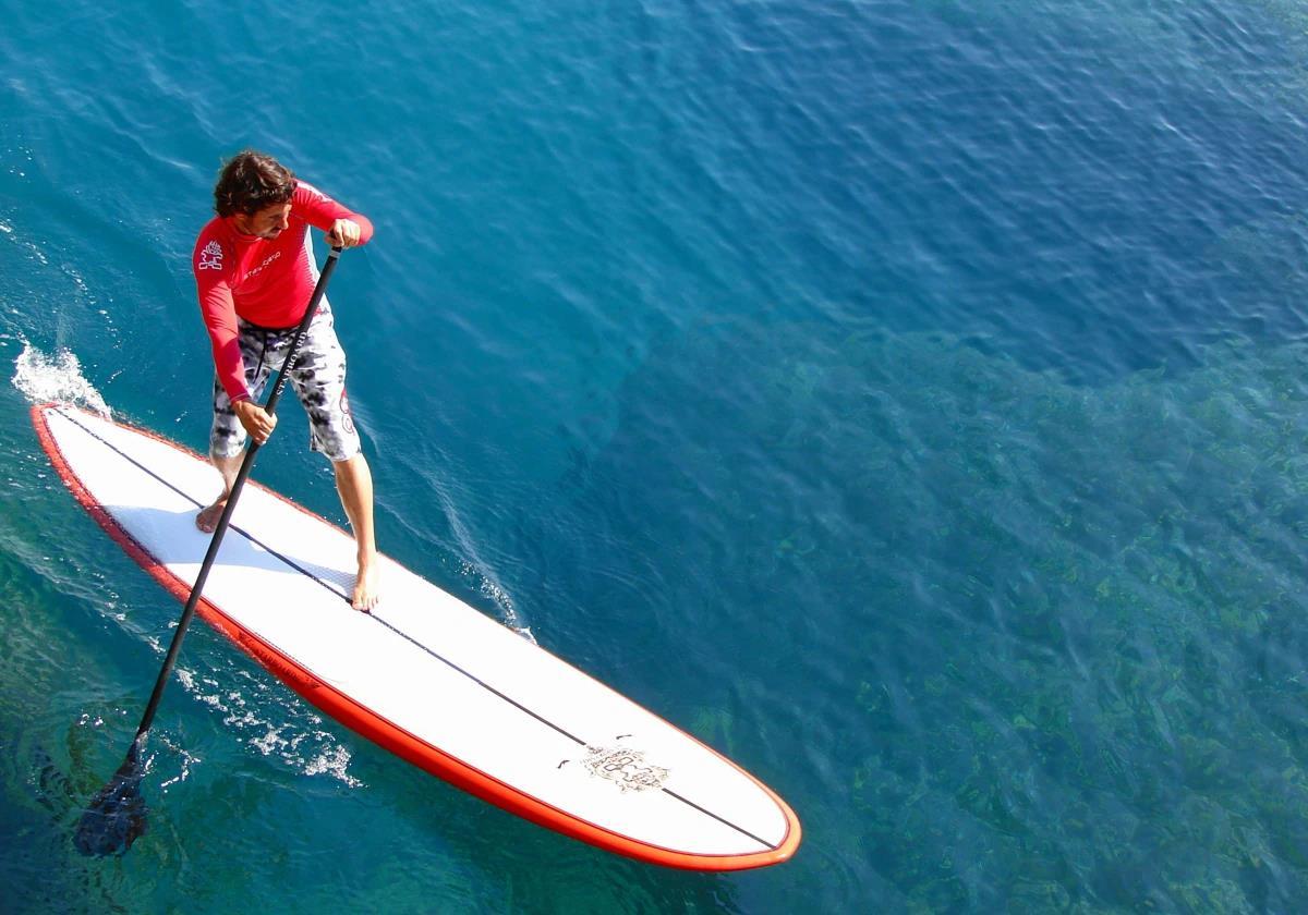 Un hombre realiza paddle surf en la playa