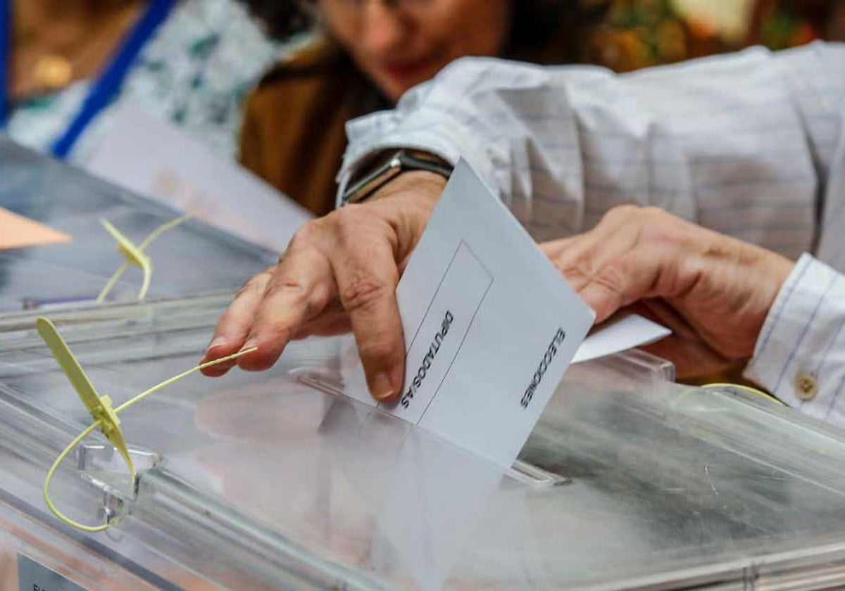 El presidente de una mesa electoral introduce el voto de un ciudadano en las últimas generales