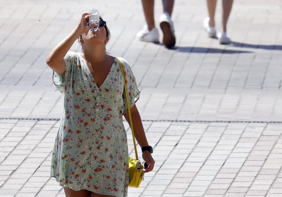 Una chica bebe agua  bajo el sol