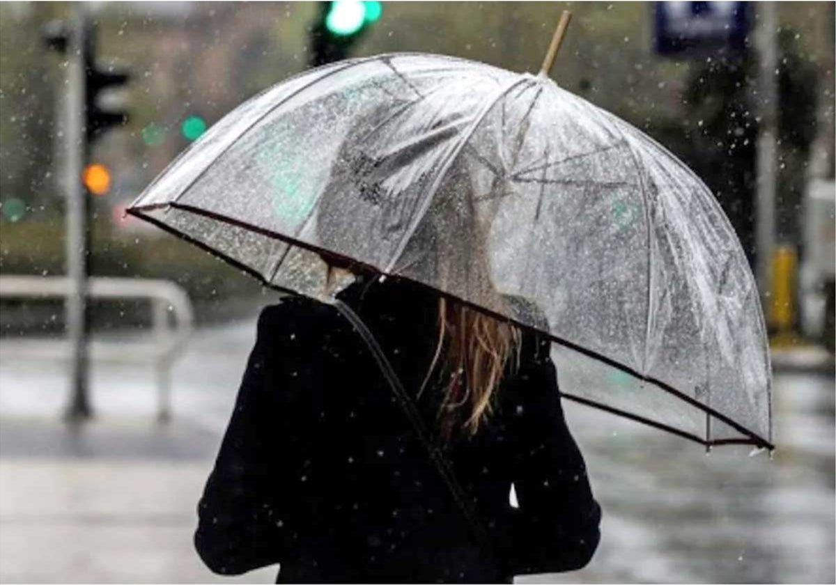 Una chica se guarece bajo un paraguas en un día de lluvia