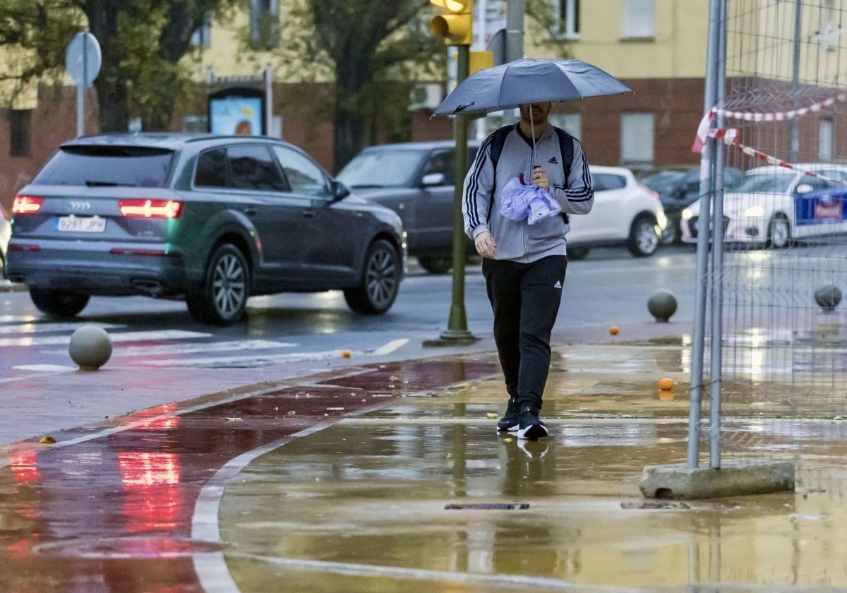 Una persona paseando este domingo por una lluviosa calle de Huelva capital