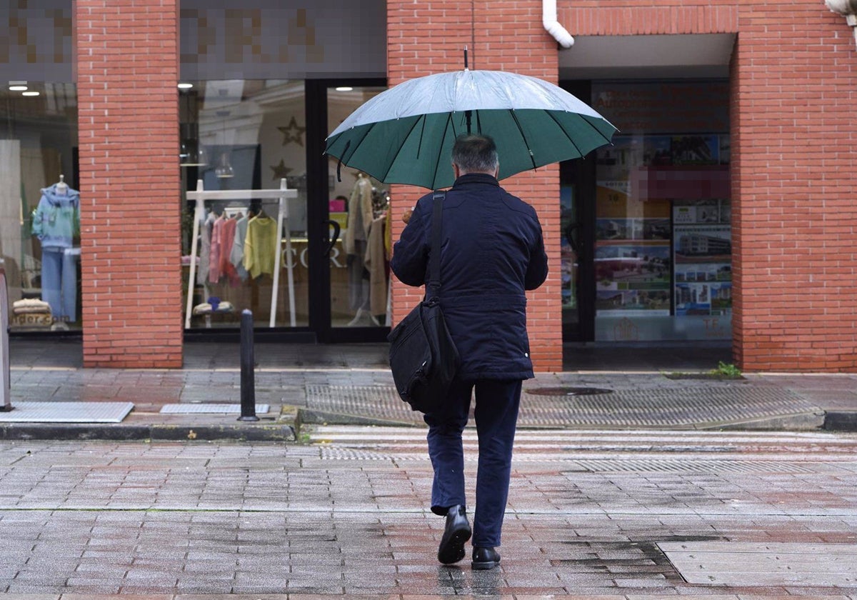 Un hombre camina protegido de la lluvia por un paraguas