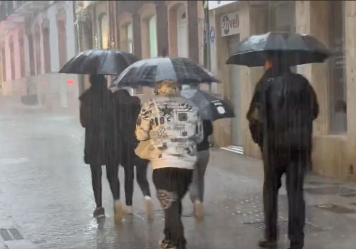 Personas bajo la lluvia por el centro de Huelva