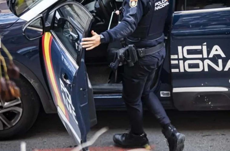 Un agente del Cuerpo Nacional de Policía junto a un vehículo patrulla
