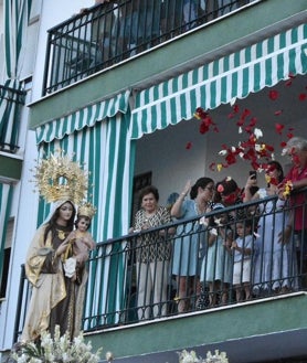 Imagen secundaria 2 - Arriba, ambientazo en la Feria de Día y sobre estas líneas, equilibrio sobre la cucaña y flores para la patrona al paso de la imagen