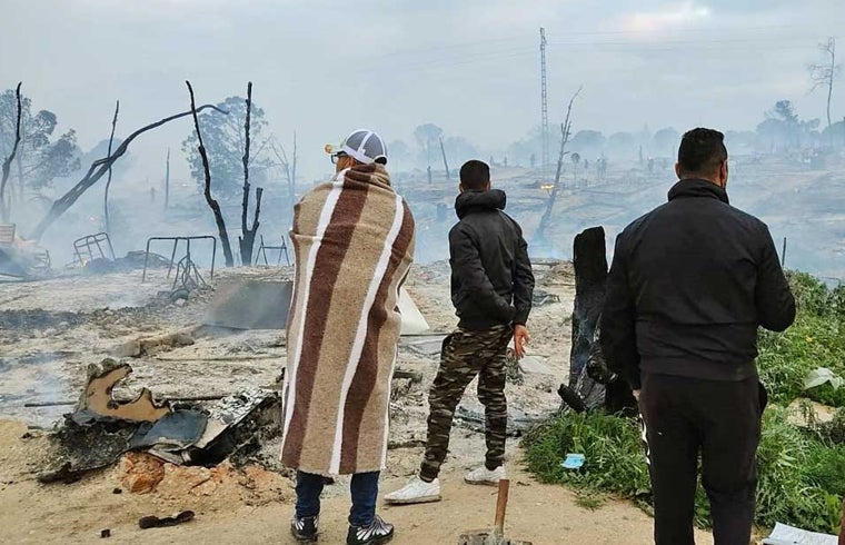 Inmigrantes tras un incendio en el asentamiento en el que residían