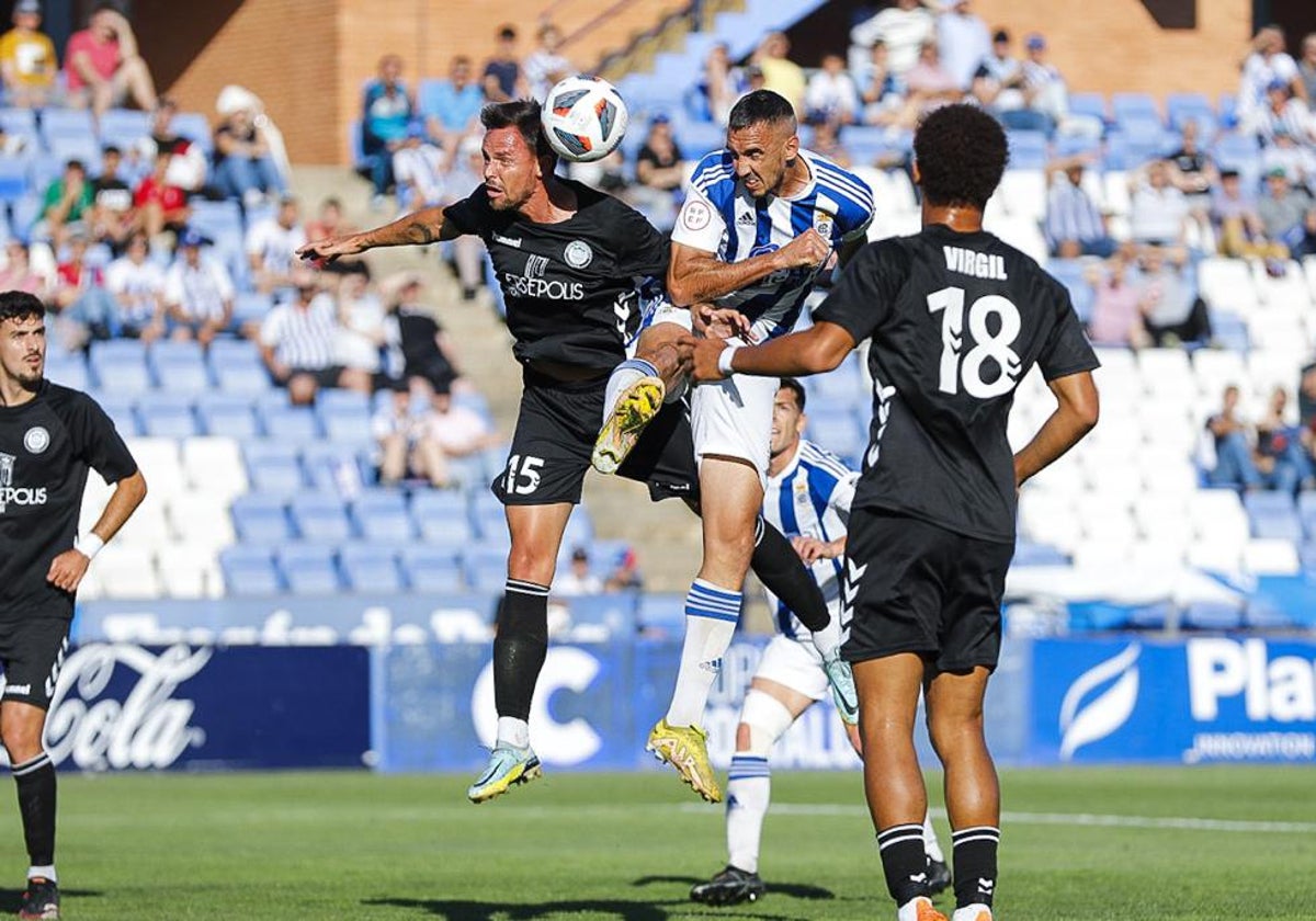 Pablo Caballero cabecea un balón ante la defensa del Torremolinos